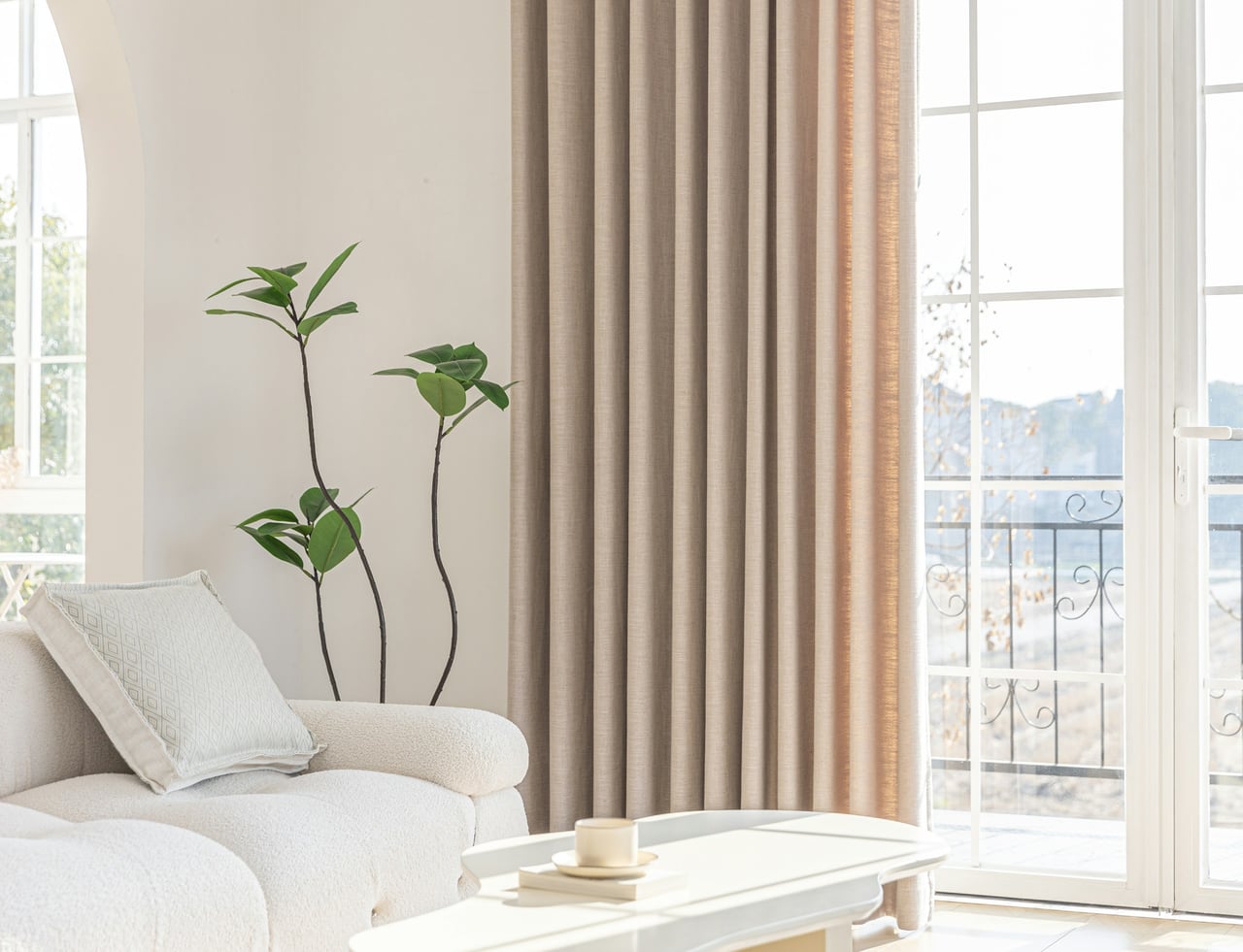 Bright living room with full-length beige curtains, textured sofa, and soft natural light