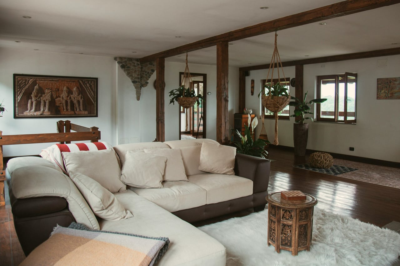 Warm living interior with layered sofa textiles, timber architecture and natural light
